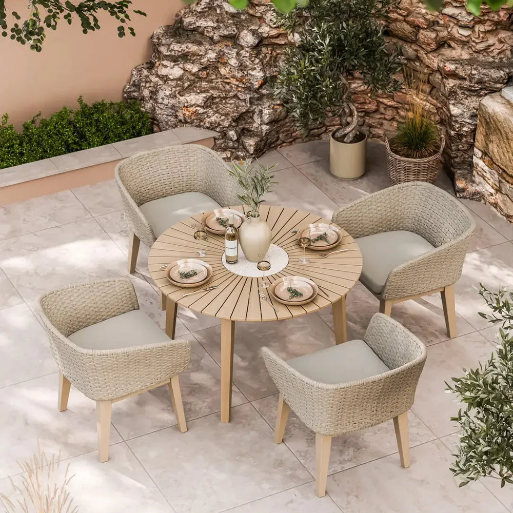Beige rattan garden dining set with round wooden table and four cushioned chairs on patio