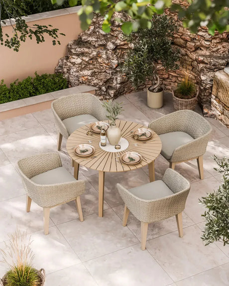 Beige rattan garden dining set with round wooden table and four cushioned chairs on patio