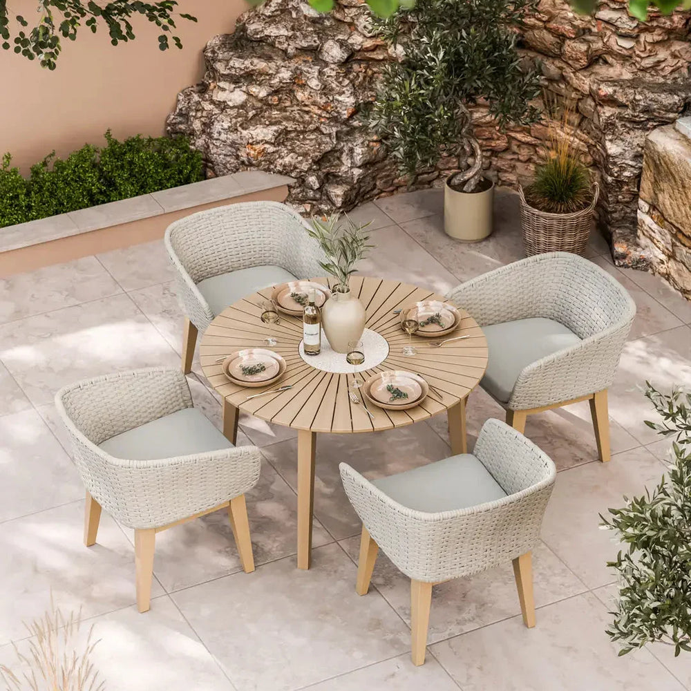 Round wooden outdoor dining table set with four wicker chairs on patio