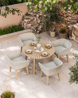 Round wooden outdoor dining table set with four wicker chairs on patio