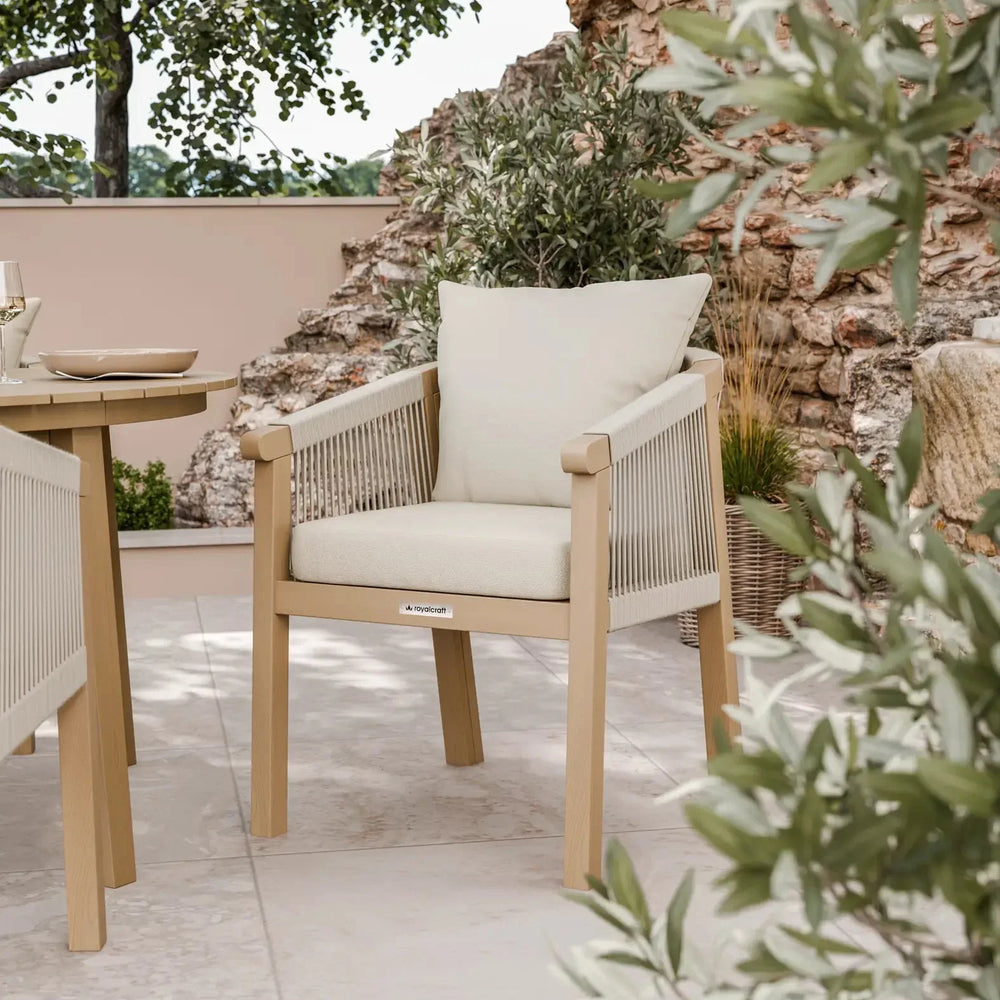 Outdoor rope dining chair with beige cushions on a tiled patio near a stone wall and plants