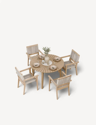 Round wooden dining table set with four woven chairs and tableware arranged on top