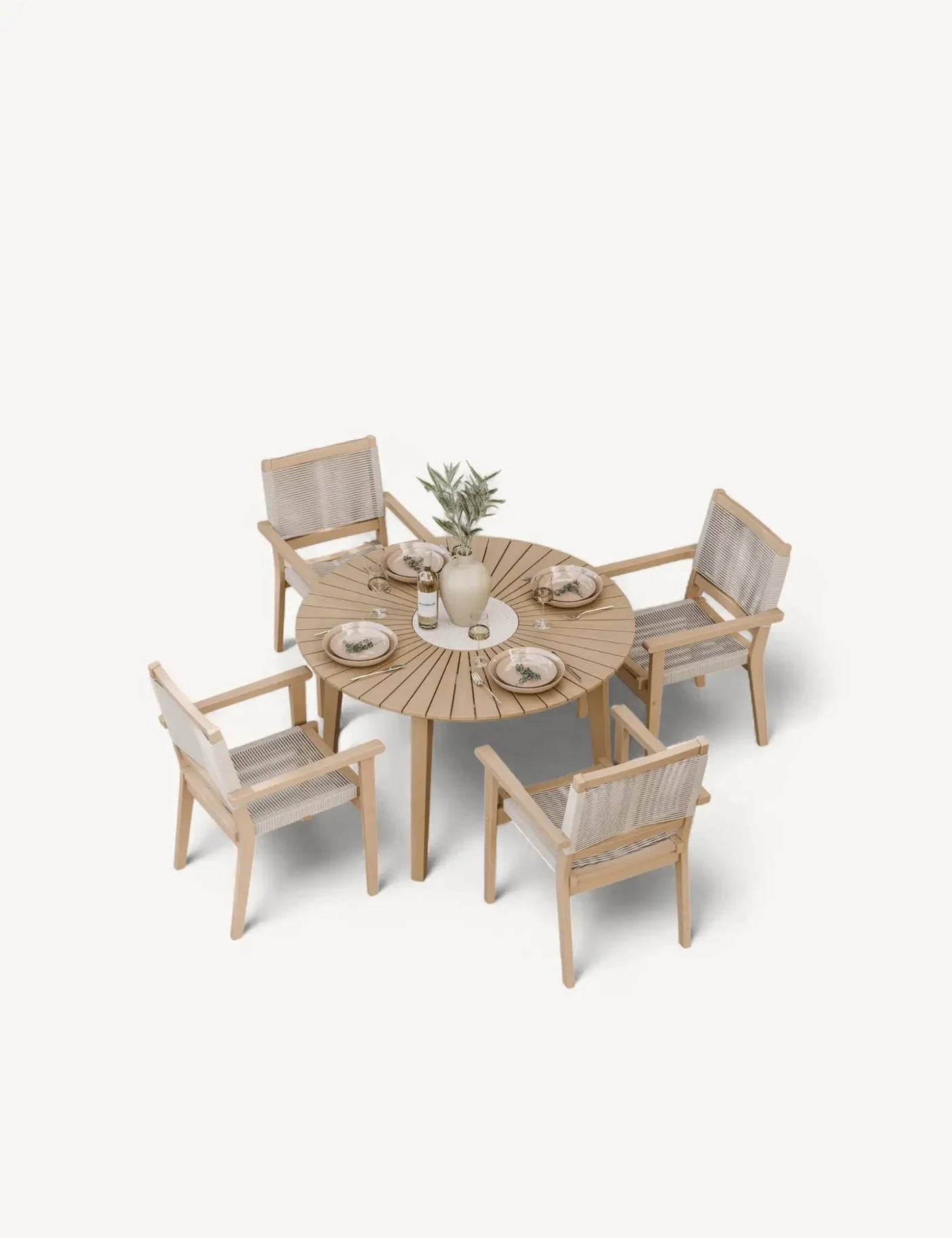Round wooden dining table set with four woven chairs and tableware arranged on top