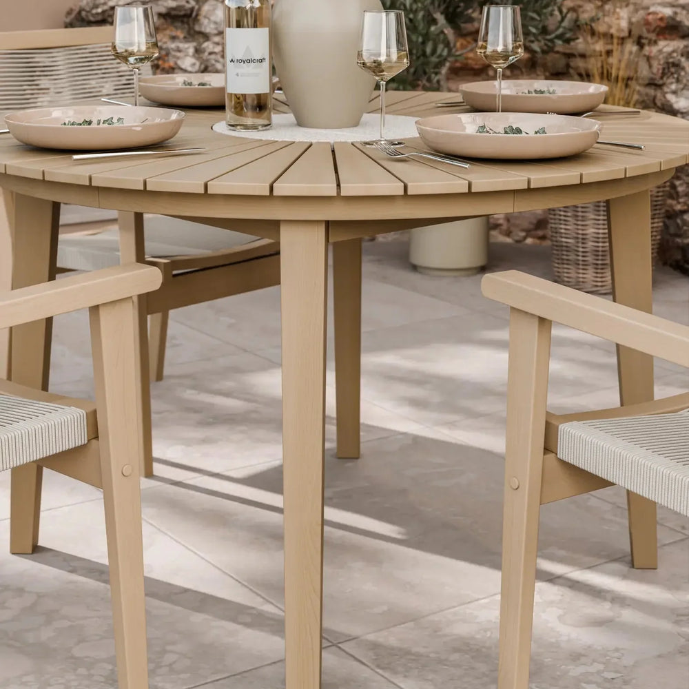 Round wooden outdoor dining table with matching chairs set for four on patio