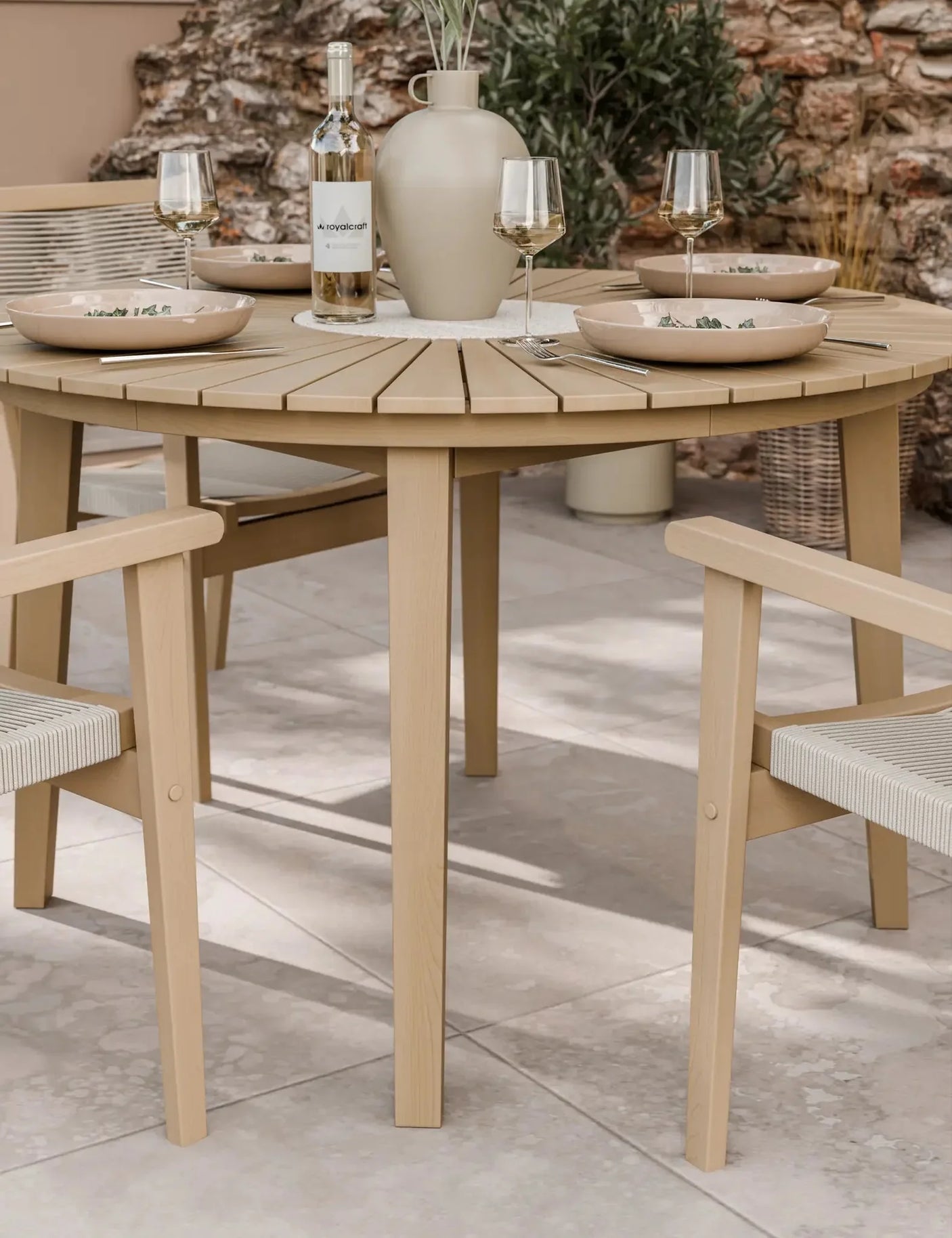 Round wooden outdoor dining table with matching chairs set for four on patio