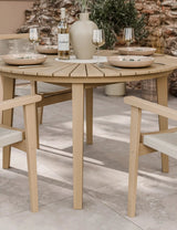 Round wooden outdoor dining table with matching chairs set for four on patio