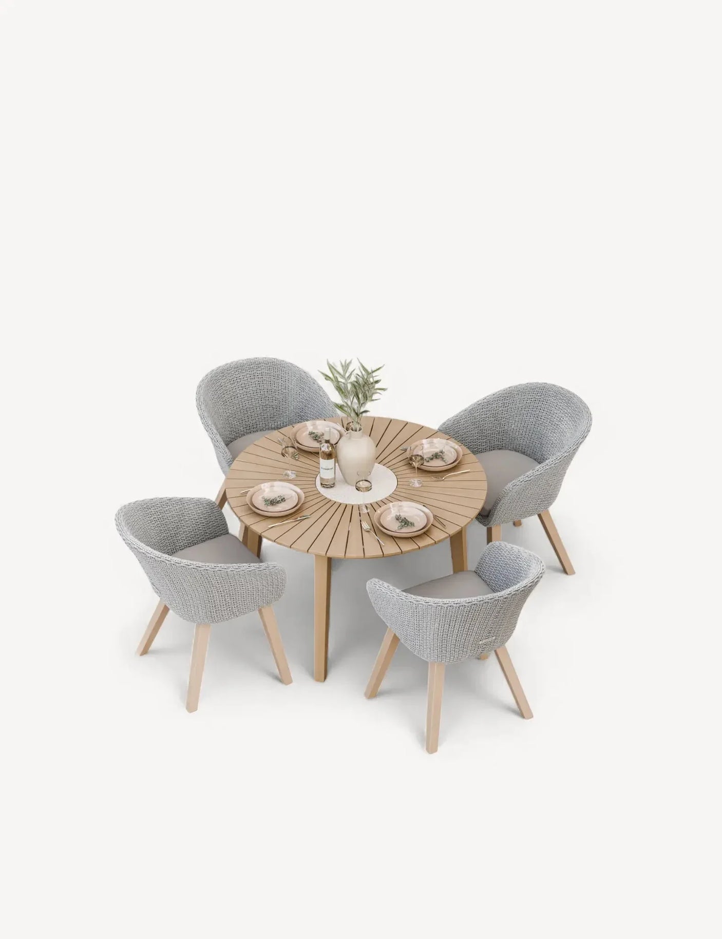 Round wooden dining table with four grey woven chairs set for a meal