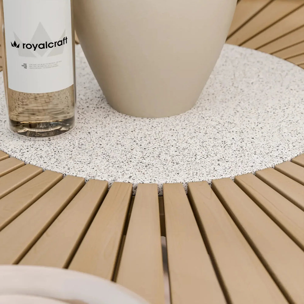 Round slatted wood dining table with speckled stone centrepiece and beige vase