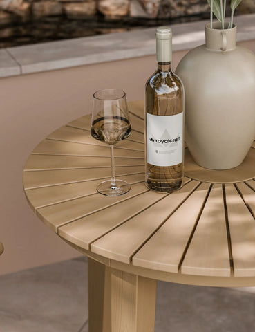 Round natural wood outdoor dining table with wine bottle, glass, and decorative vase