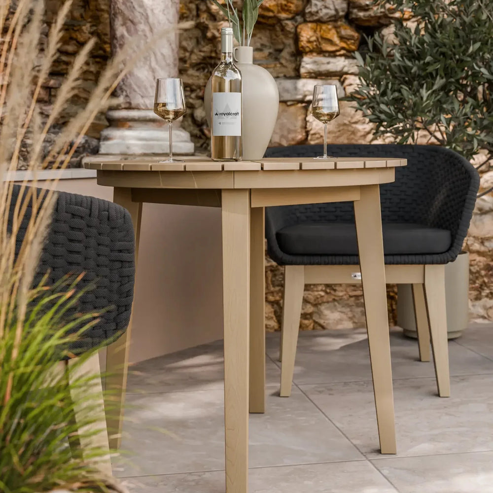 Beige outdoor dining table with wine bottle and glasses, paired with black woven chairs
