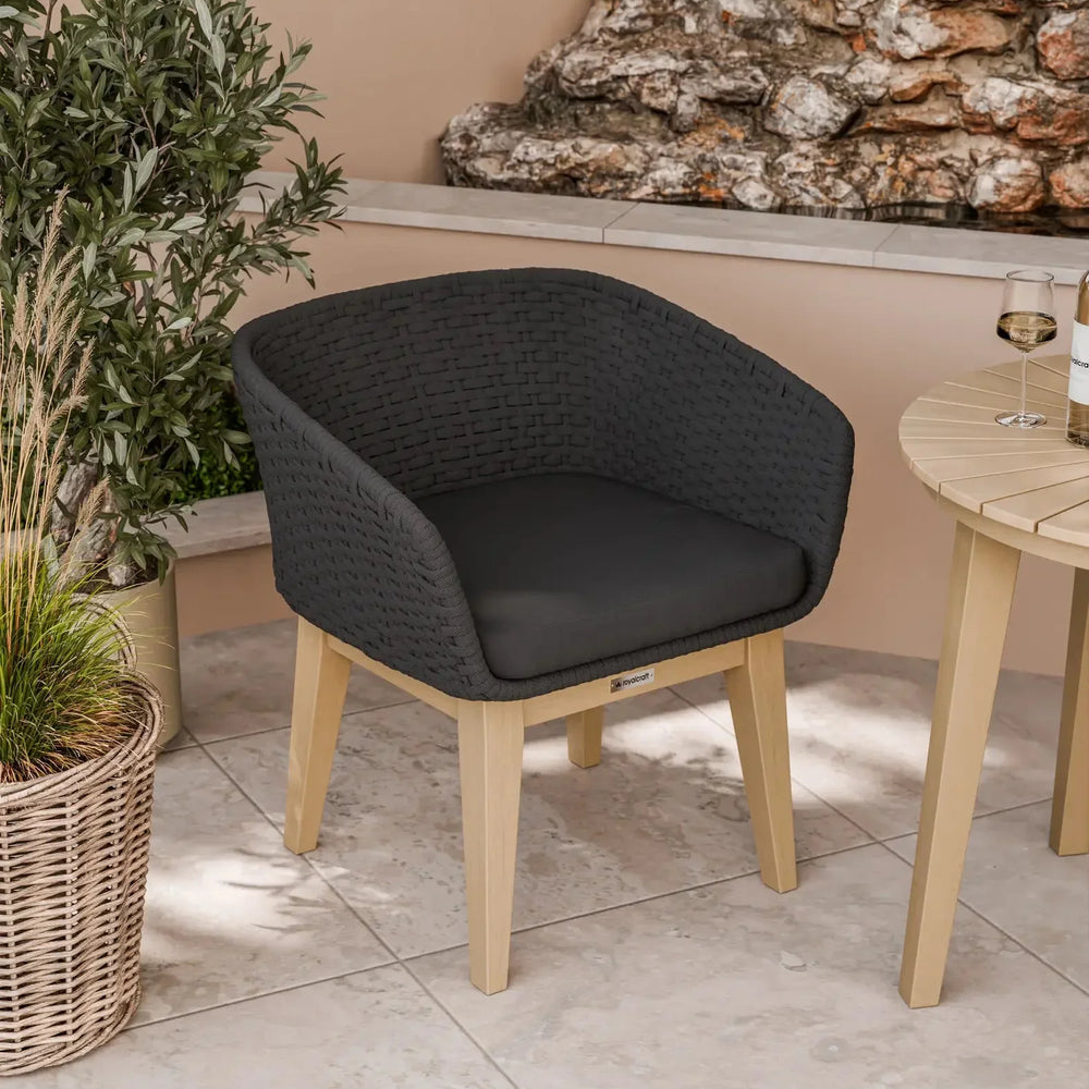 Black rattan outdoor dining chair with wooden legs on patio beside round table