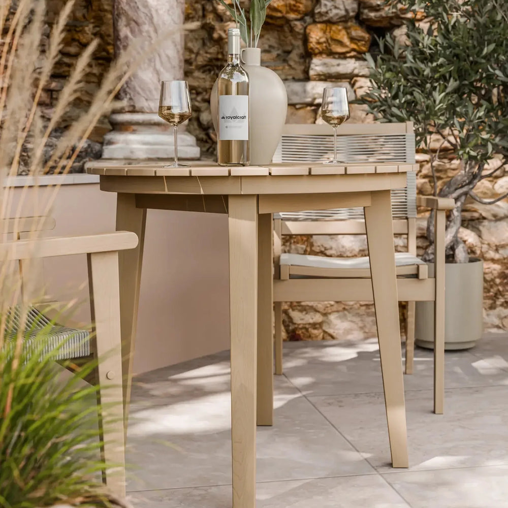 Outdoor wooden dining table and chair set with wine bottle, glasses, and vase on patio