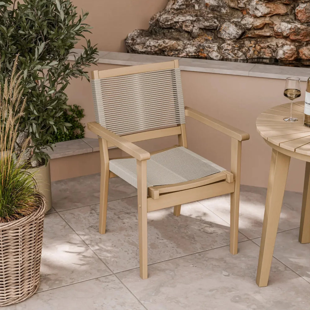 Beige outdoor dining chair with rope seat and backrest on tiled patio beside round table