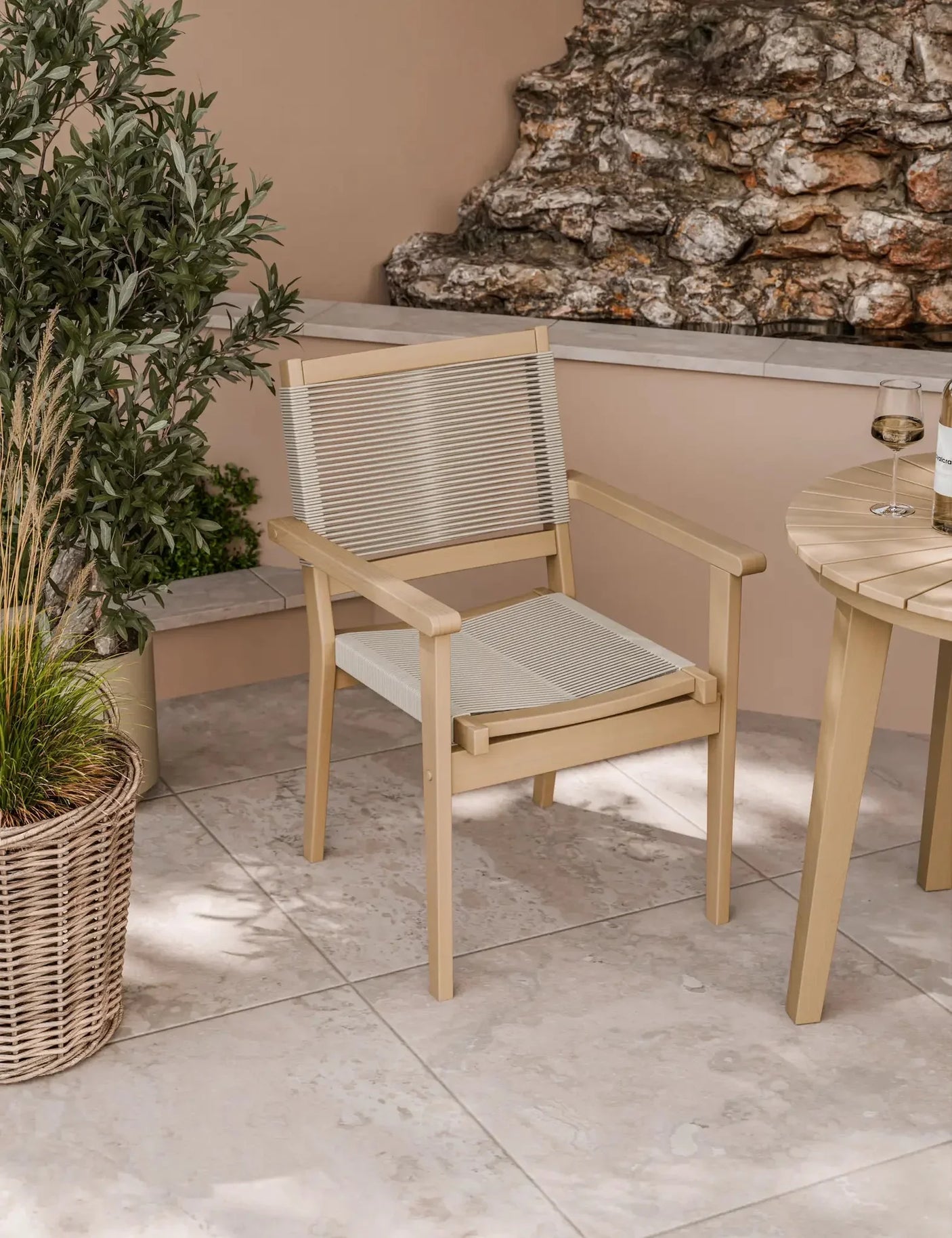 Beige outdoor dining chair with rope seat and backrest on tiled patio beside round table