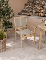 Beige outdoor dining chair with rope seat and backrest on tiled patio beside round table