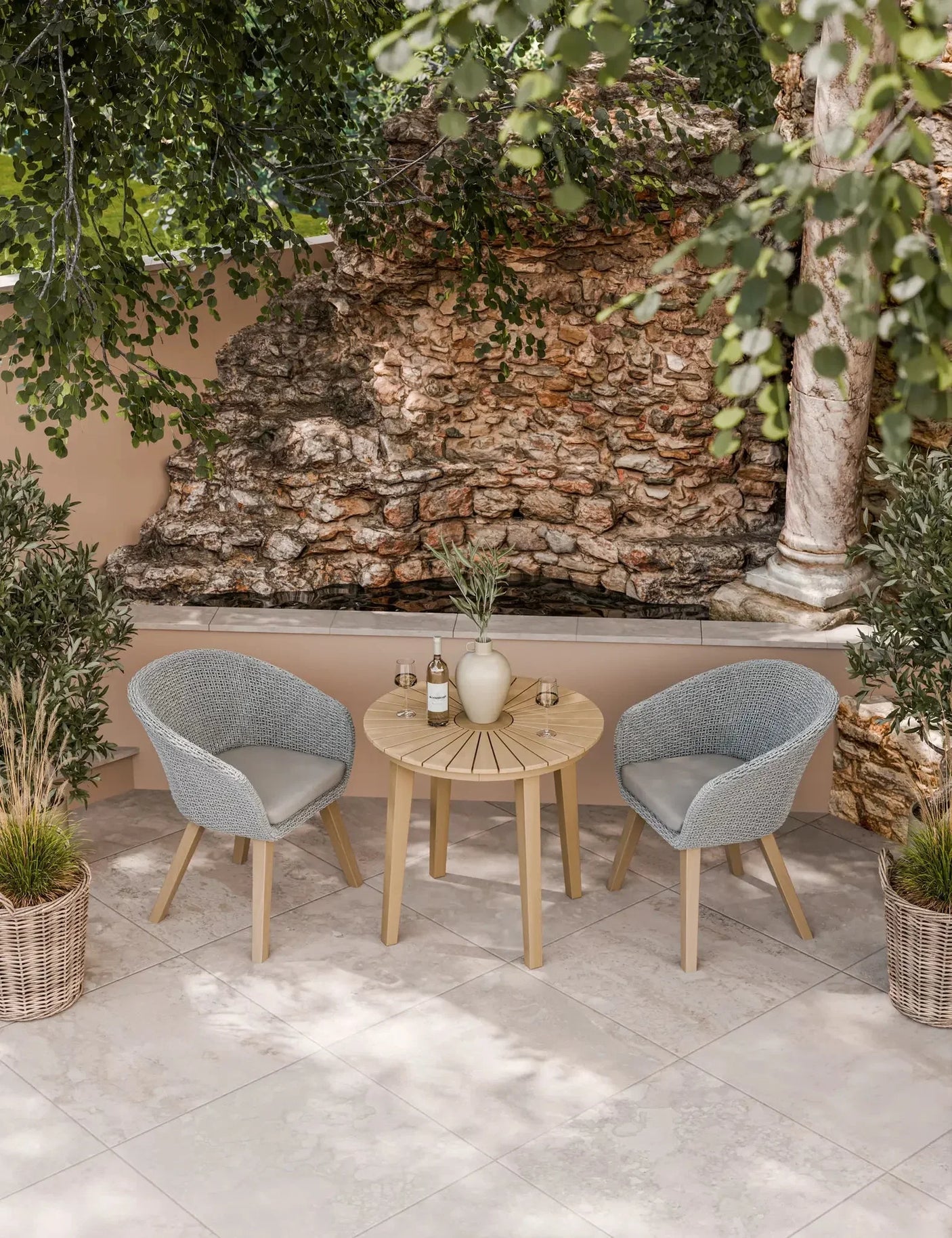 Outdoor bistro set with round wooden table and two grey rattan chairs on patio tiles
