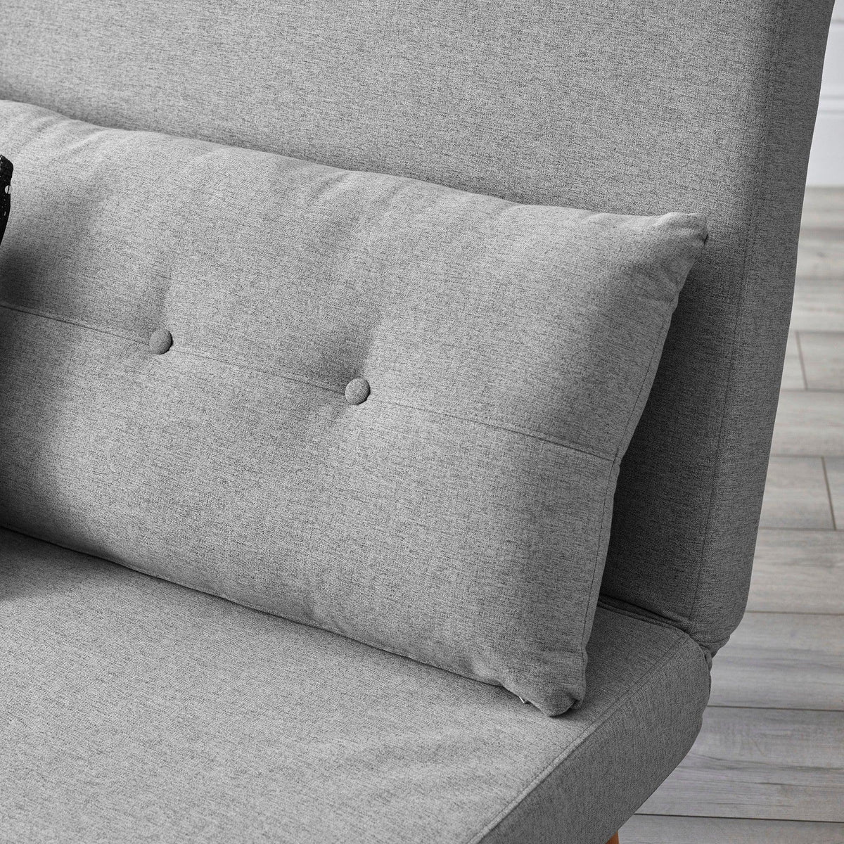 Close view of grey single sofabed upholstery with textured cushion and button detail