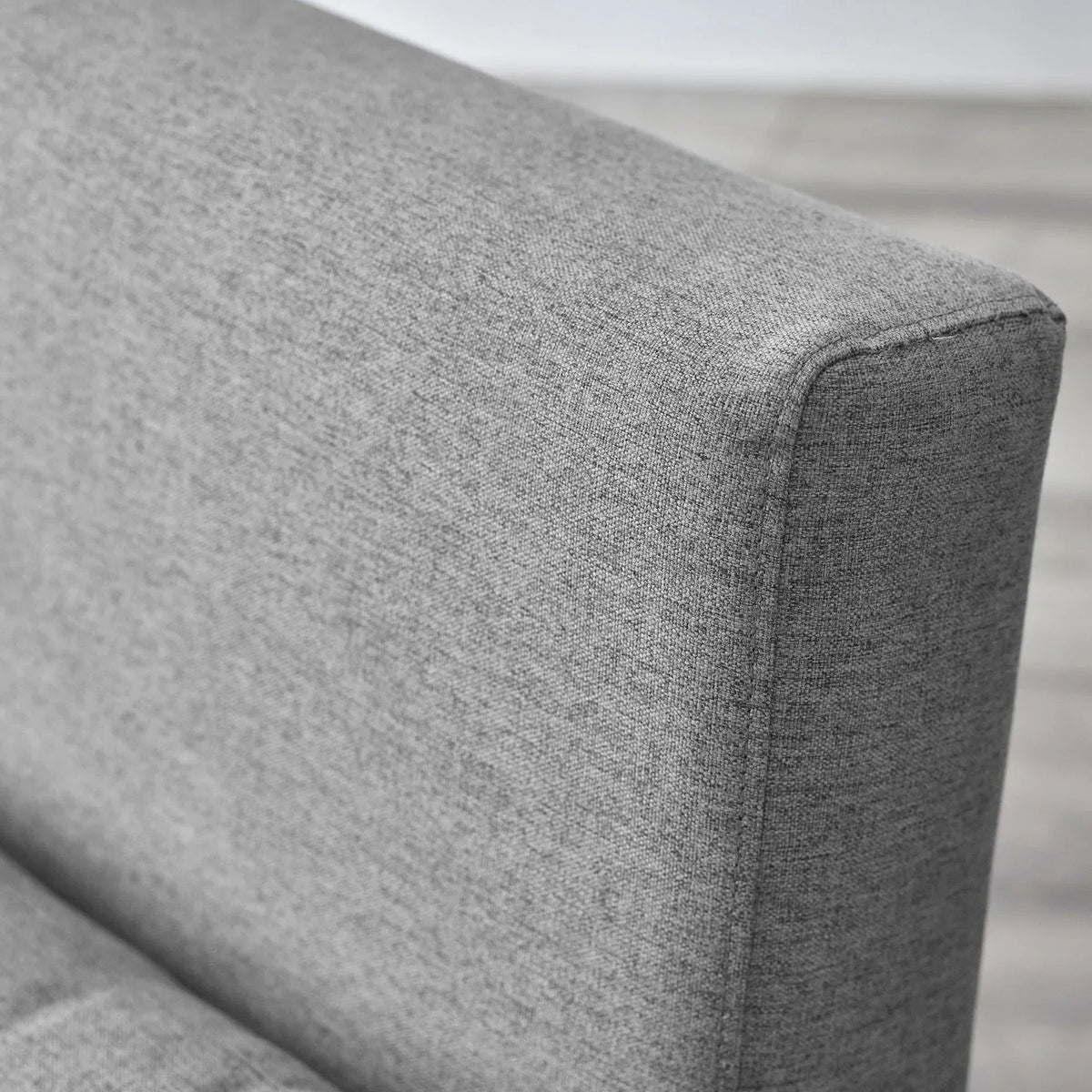 Close-up of grey sofabed armrest with textured fabric upholstery