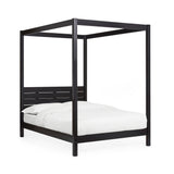 Black wooden canopy bed with white bedding shown at an angle on a white background