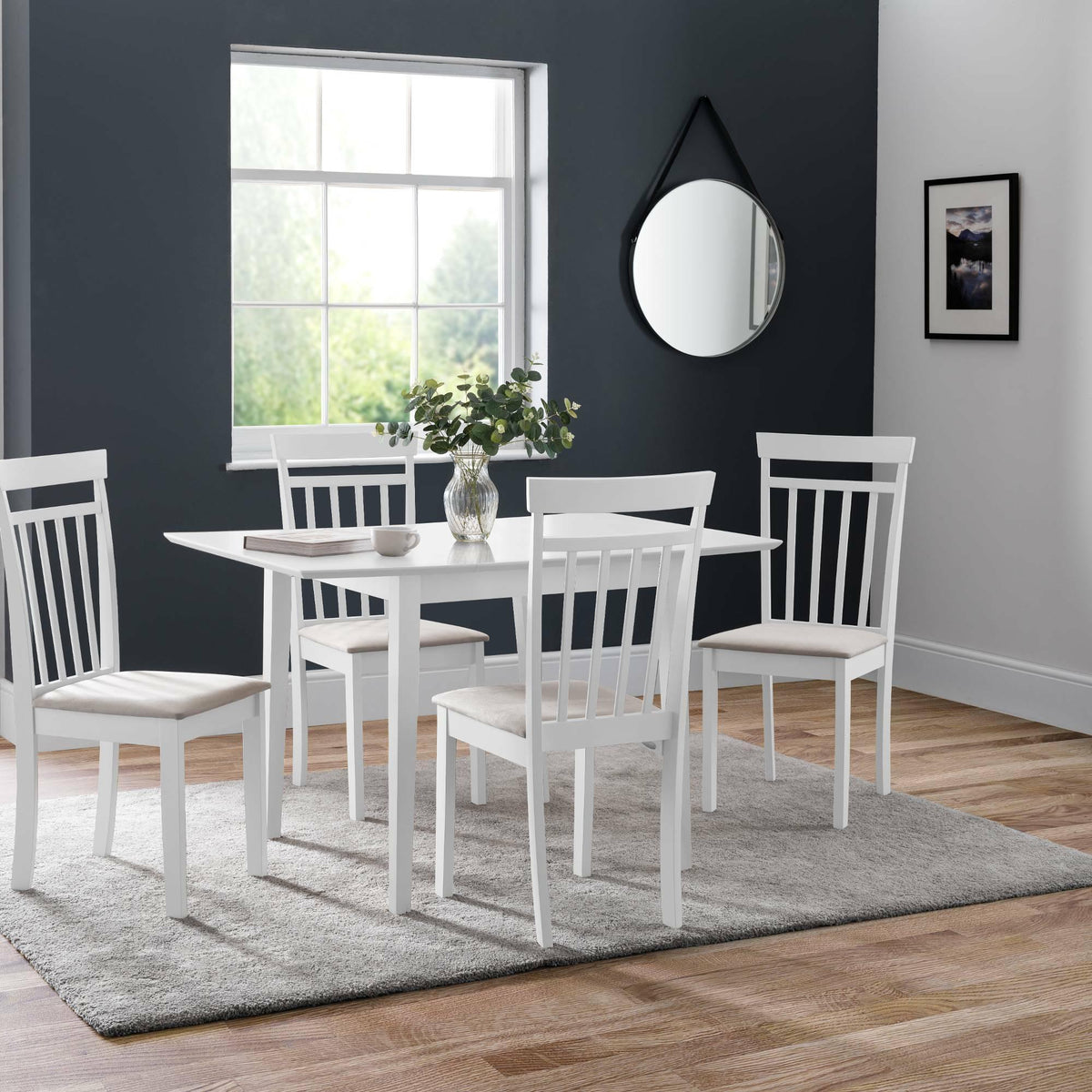 White dining table with four matching chairs on grey rug beside window in modern dining room