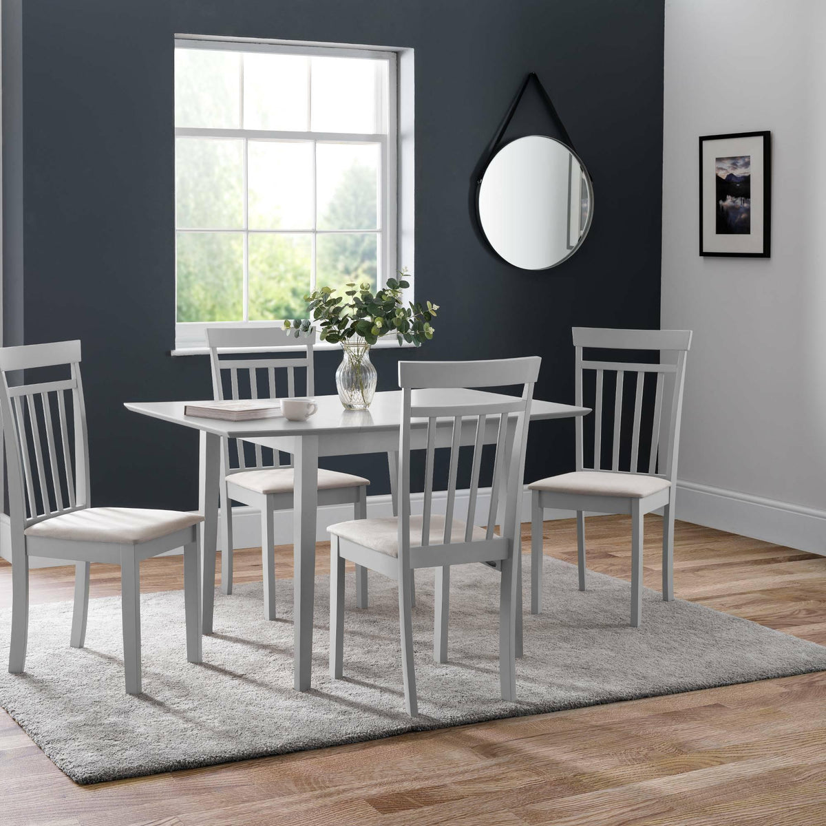 Grey wooden dining table set with four chairs on light rug in modern dining room