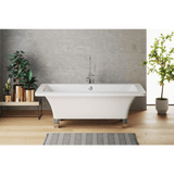 Modern freestanding bathtub in a bathroom with plants and a gray wall.