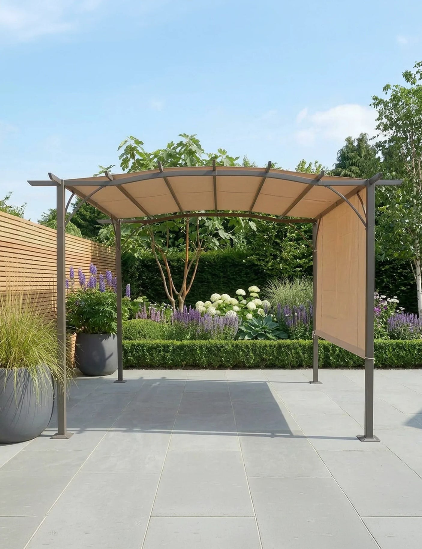 Beige garden gazebo with metal frame on patio, side panel down, surrounded by plants