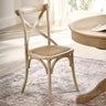 Light wooden dining chair with cane seat angled in bright room near round wooden table