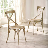 Two light wooden dining chairs with cane seats angled in sunlit room with sheer curtains