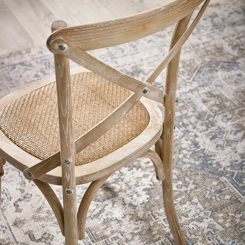 Light wood dining chair with woven seat and curved backrest showing X-shaped support and metal screws