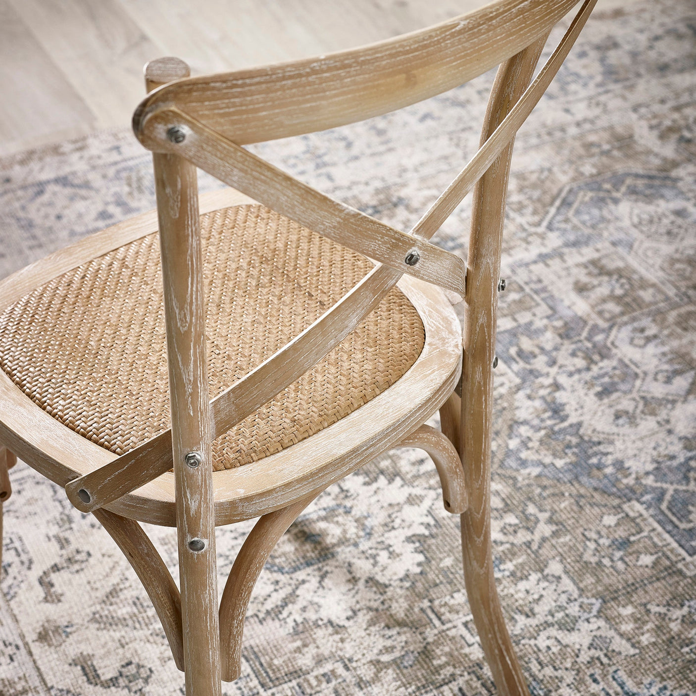 Light wood dining chair with woven seat and curved backrest showing X-shaped support and metal screws