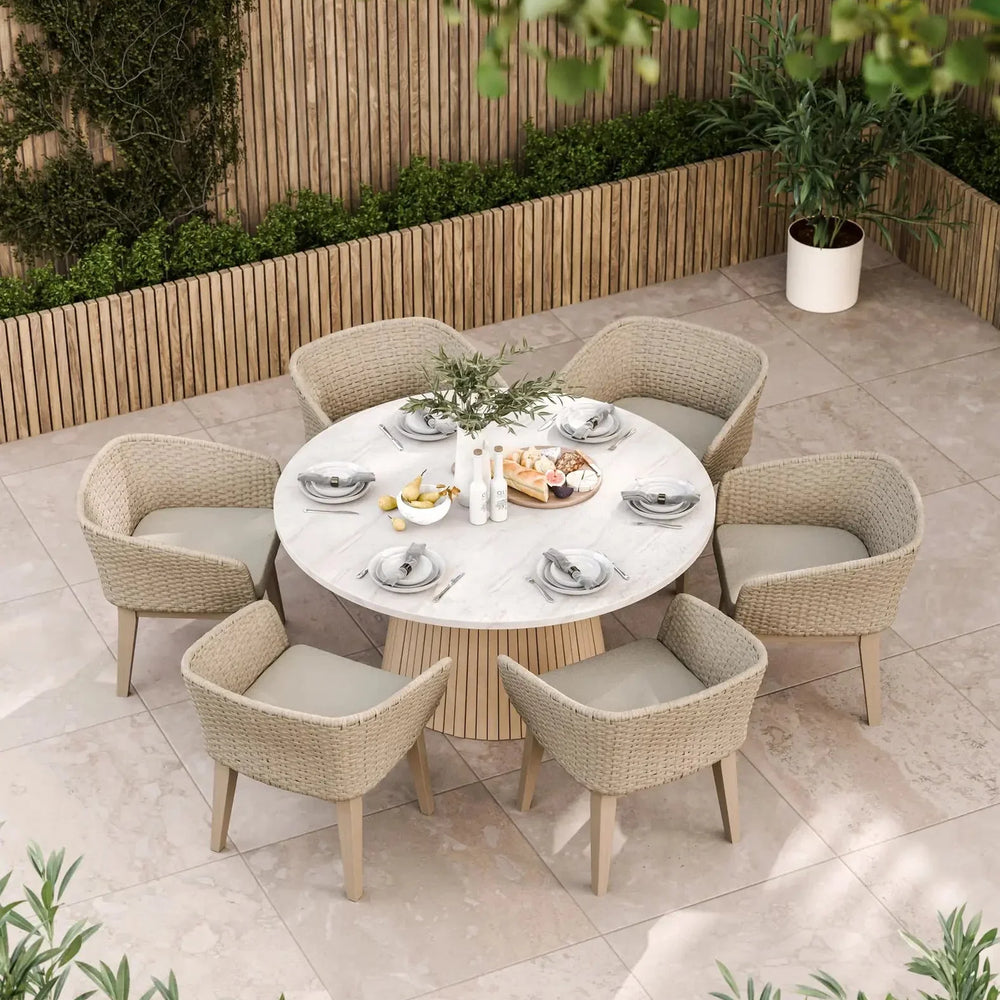 Round outdoor dining set with six woven armchairs and marble table on tiled patio
