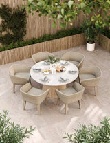 Round outdoor dining set with six woven armchairs and marble table on tiled patio