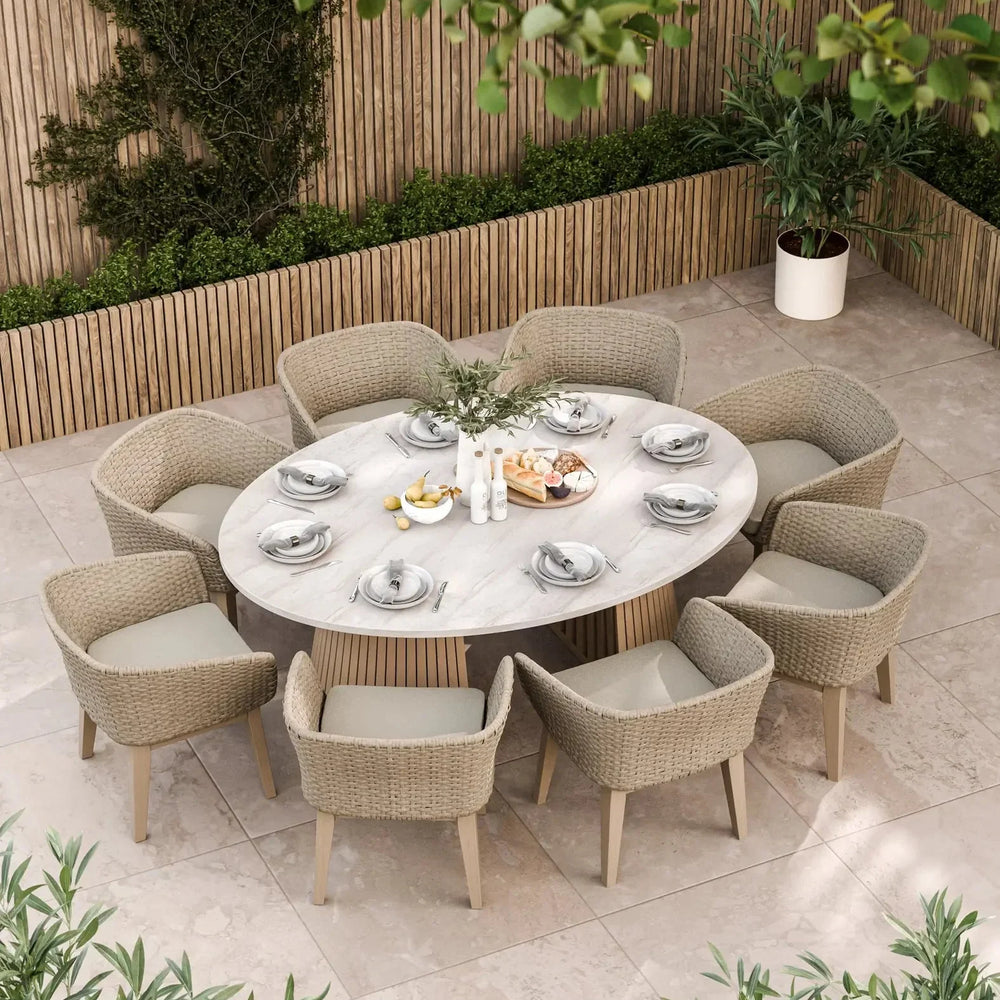 Round outdoor dining set with eight rattan chairs and marble table on tiled patio