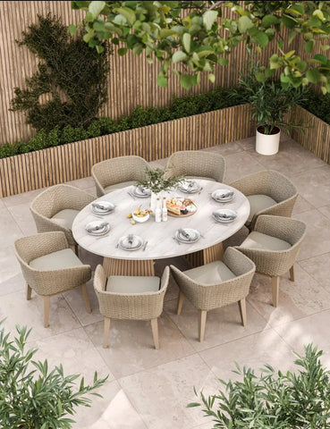 Round outdoor dining set with eight rattan chairs and marble table on tiled patio