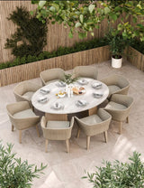 Round outdoor dining set with eight rattan chairs and marble table on tiled patio