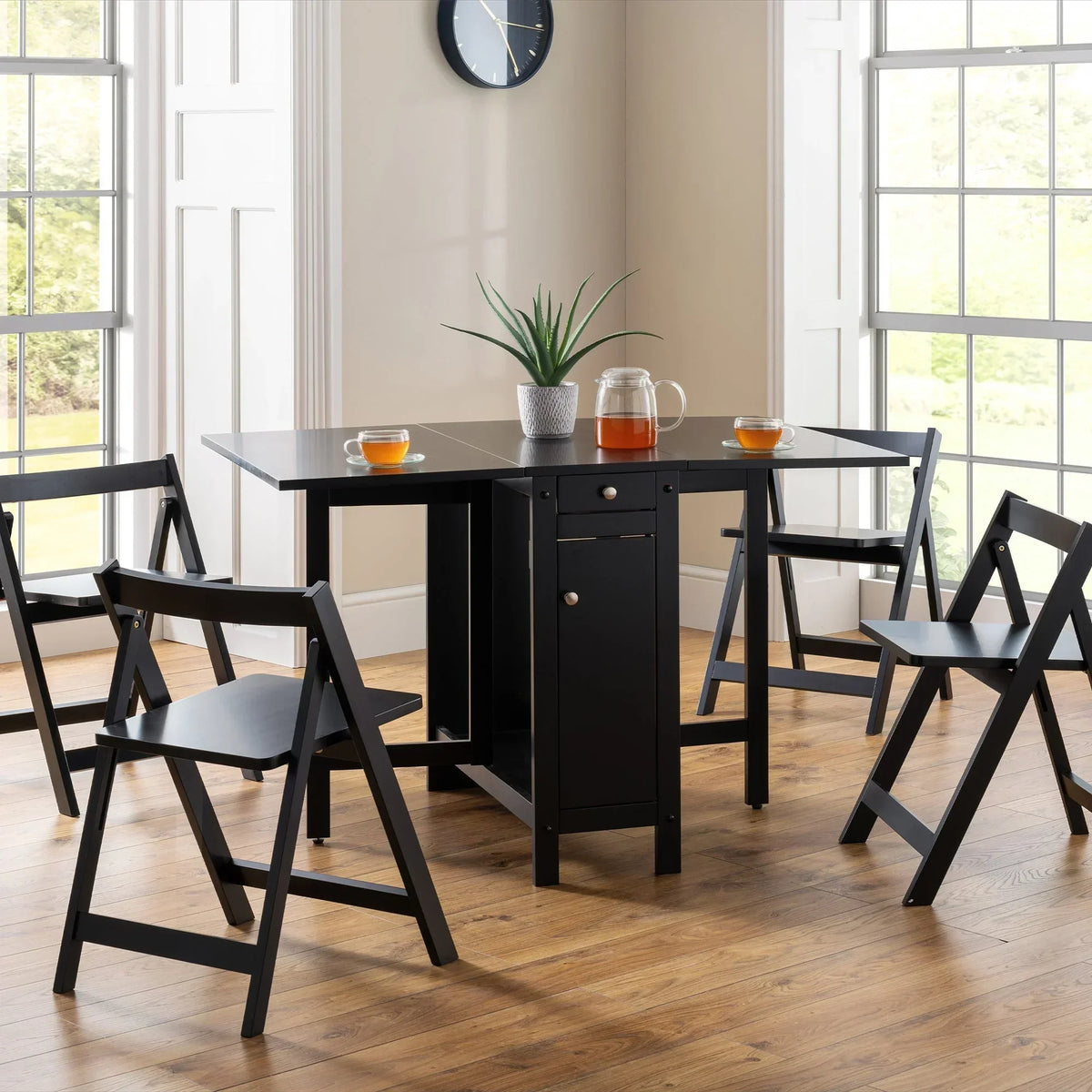 Black dining set with folding chairs around rectangular table in a bright dining room