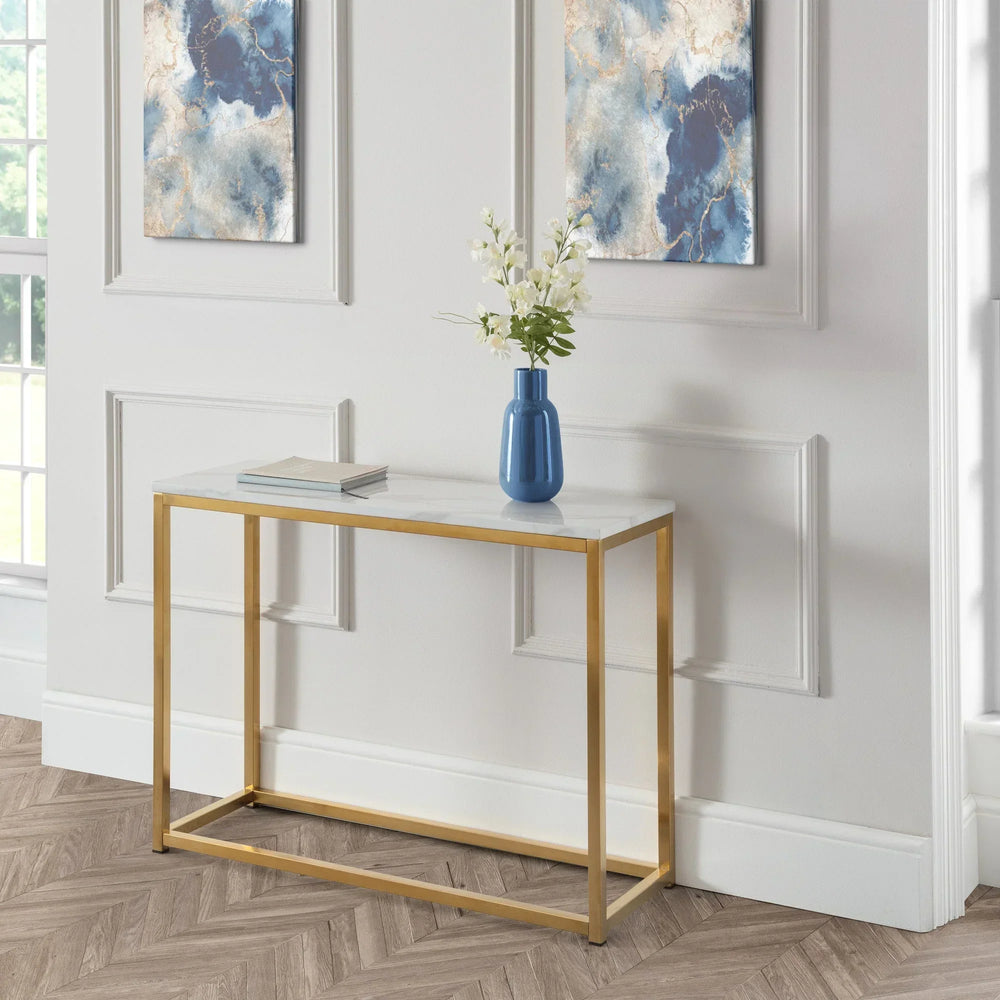 Marble top console table with gold metal frame, blue vase and book in modern hallway