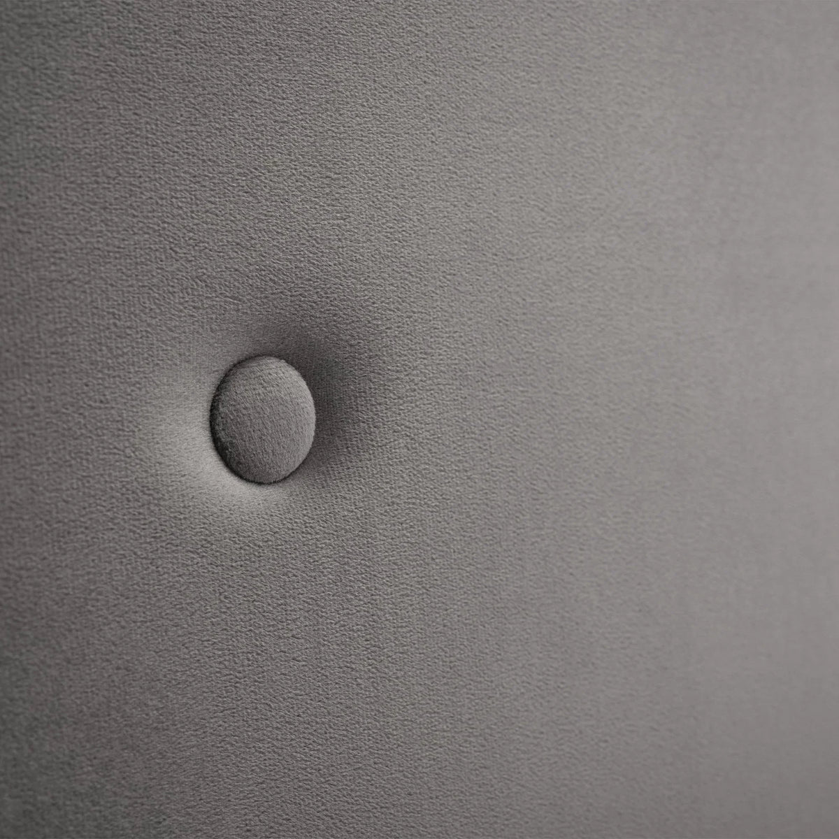 Close-up of grey upholstery on storage bed headboard with button detail