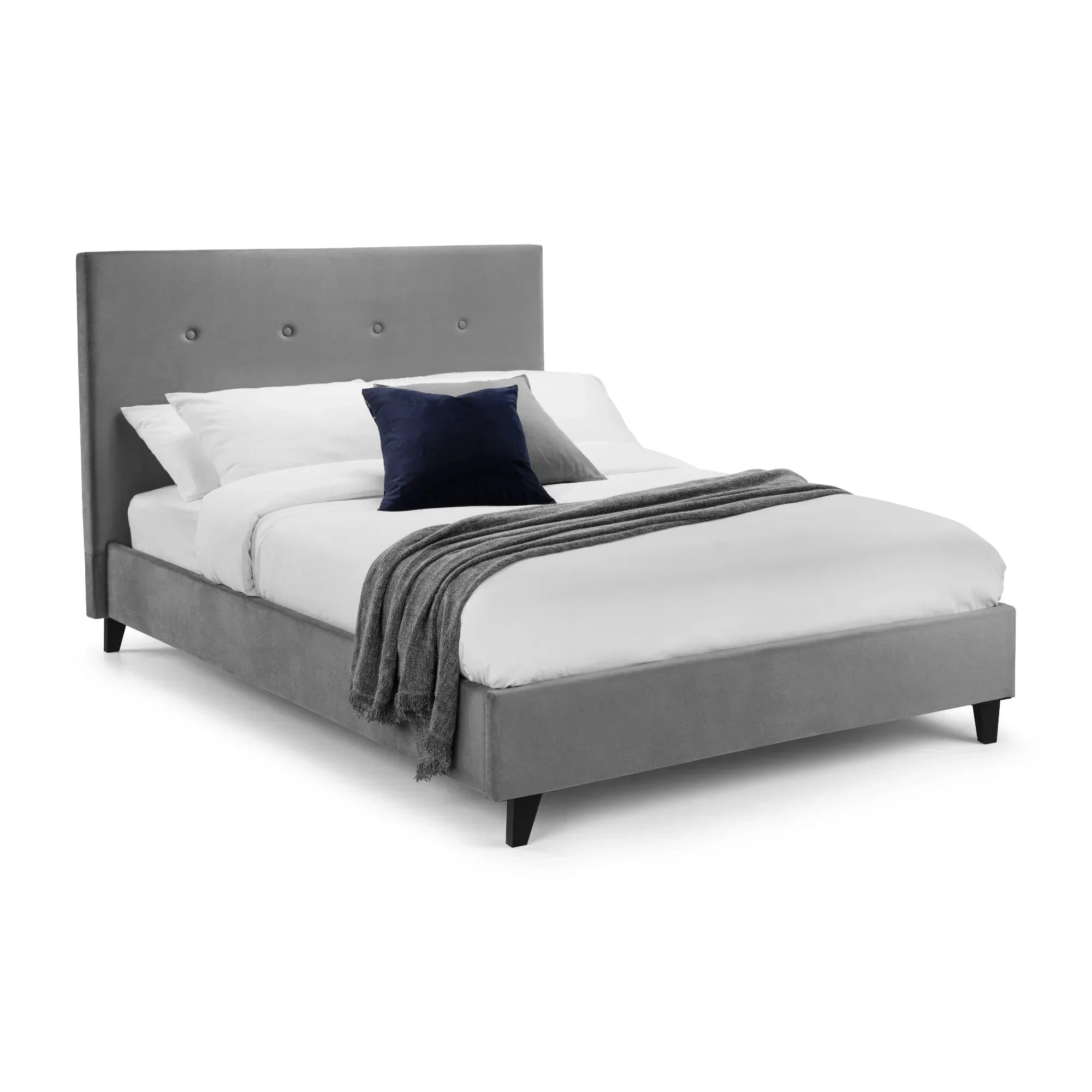 Grey upholstered bed with high headboard, white bedding, and navy cushion, angled view