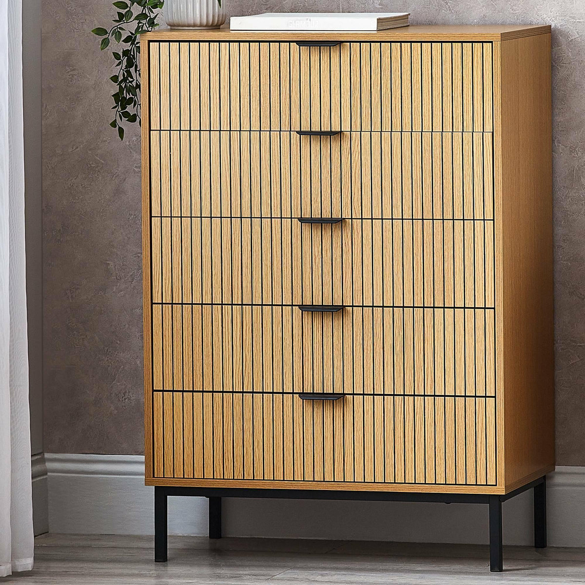 Sia 5 drawer chest with vertical wood slats and black legs against a textured wall