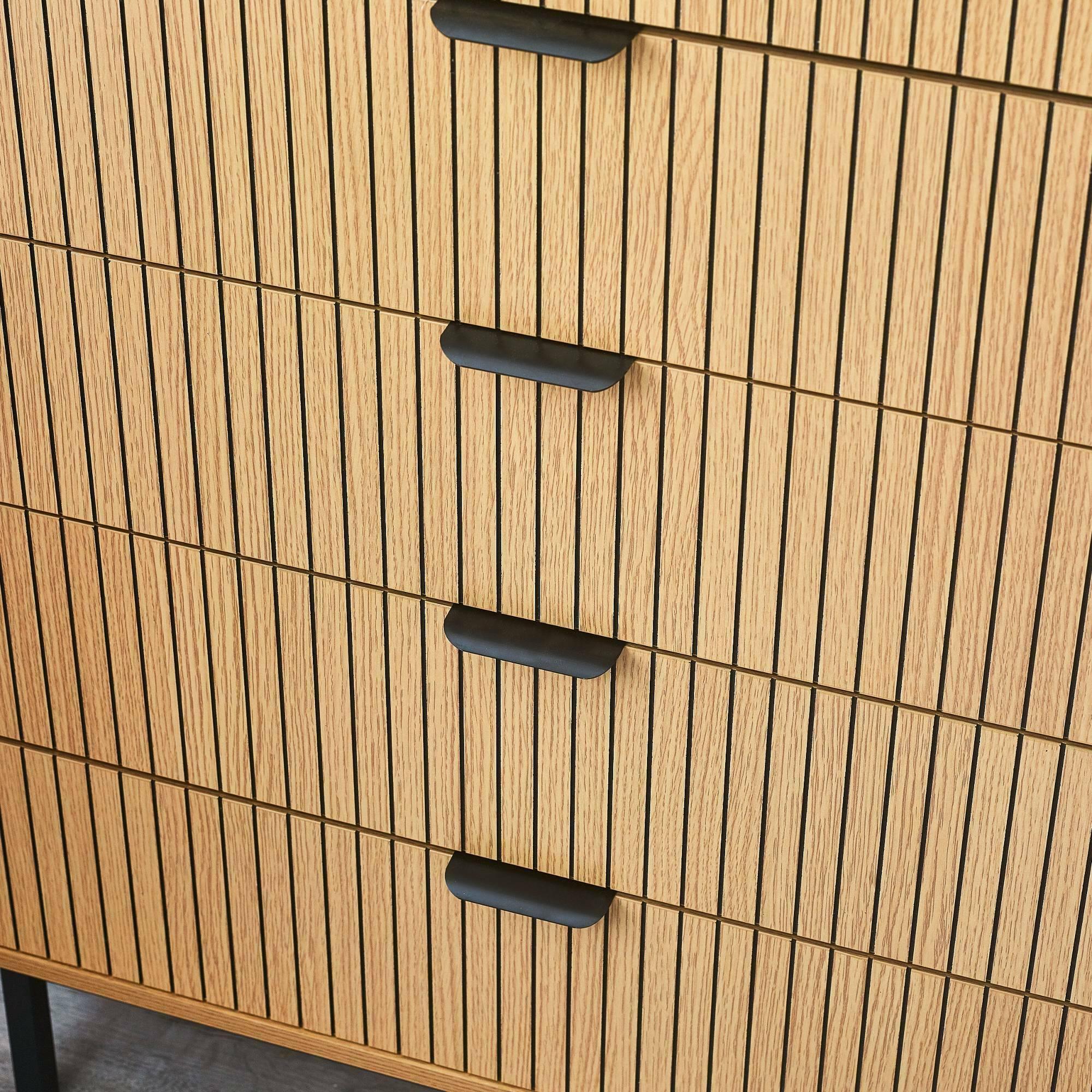 Wooden chest of drawers with vertical slatted design and black handles close up