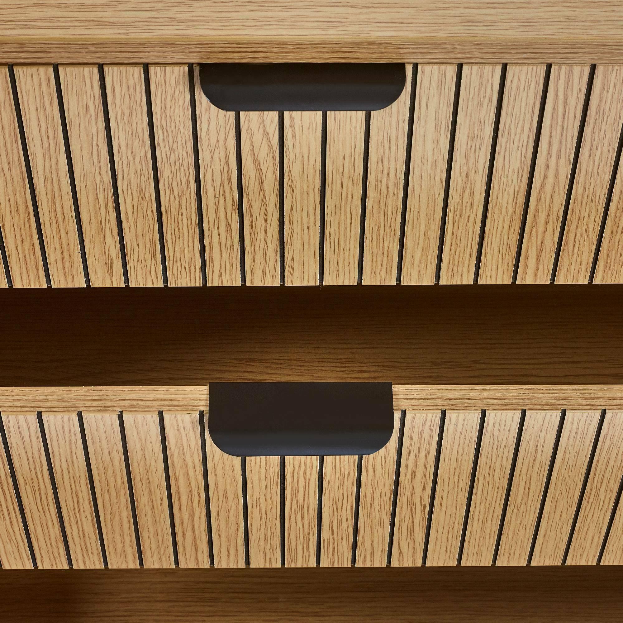 Closeup of wooden cabinet drawer fronts with vertical slat design and matte black handles