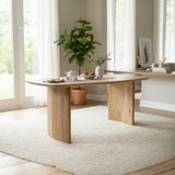 Wooden dining table with a plant and small items in a bright room.