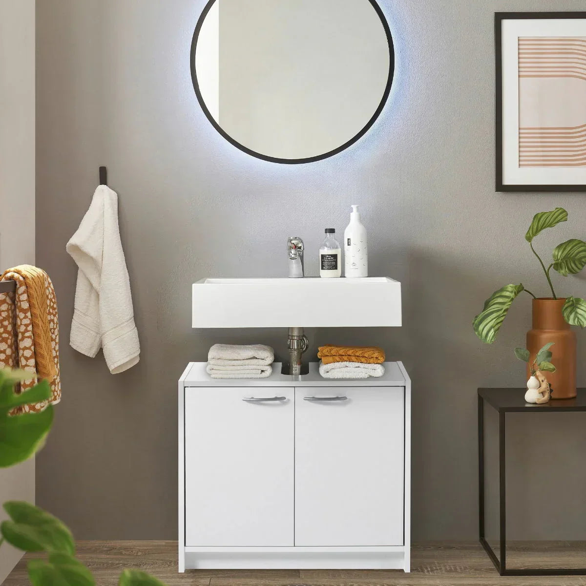White under sink unit with storage and towels in modern bathroom setting