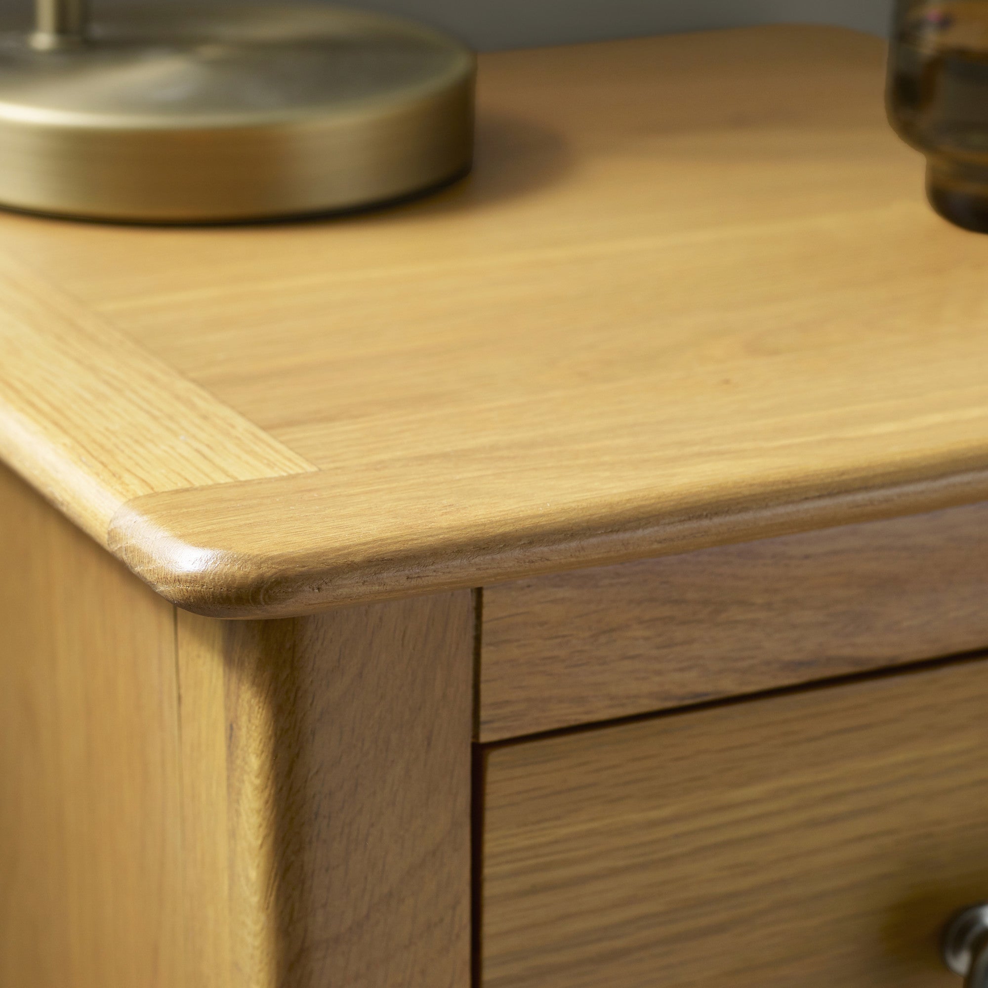 Close up of top corner of light oak bedside table showing mitred edging and wood grain detail