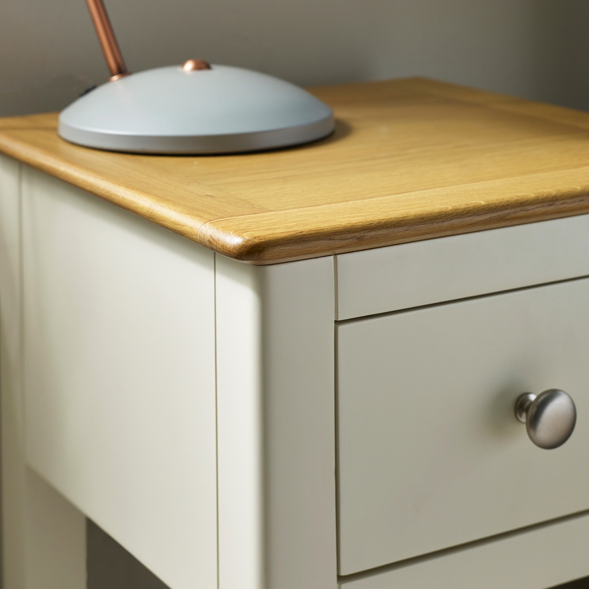 Corner detail showing oak table top edges and cream painted drawer with metal knob