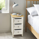 Cream colored 3 drawer bedside next to wooden bed, all three drawers pulled open