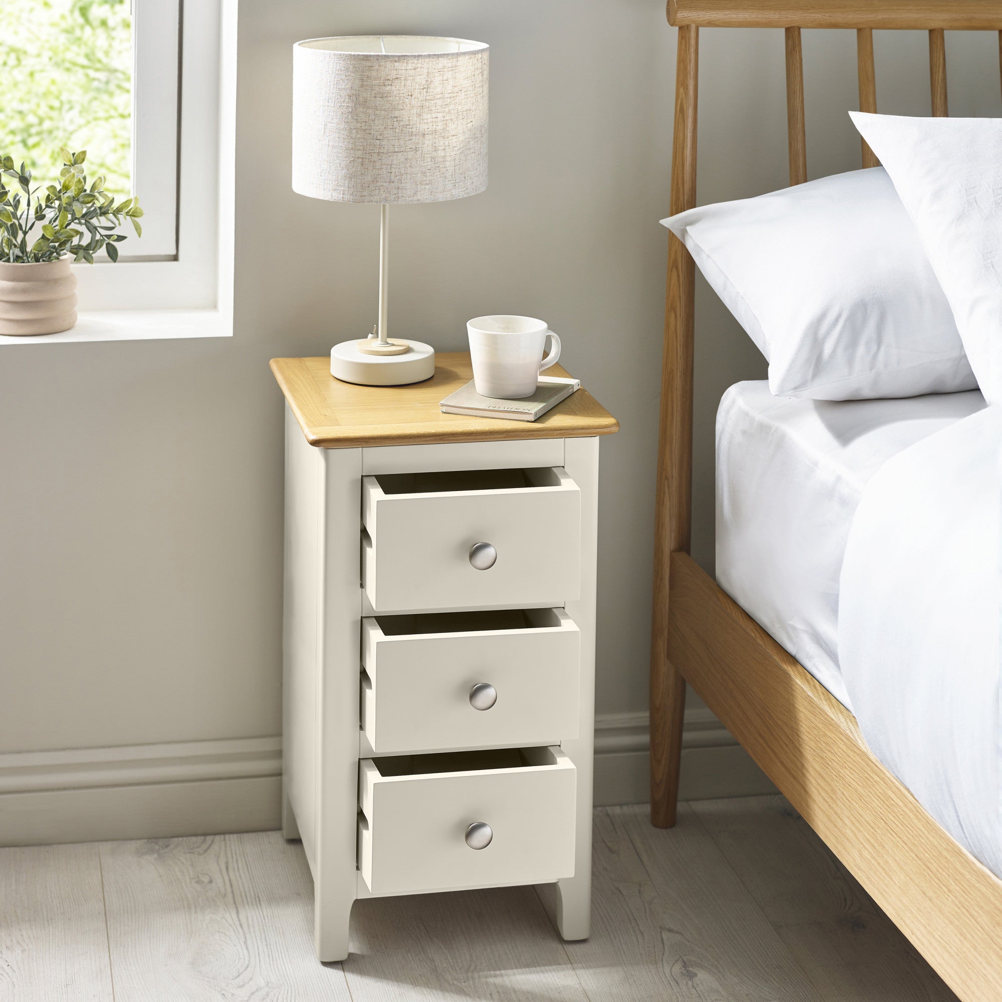 Same bedside as index 5 with drawers pulled out beside bed, lamp, white mug and book on top