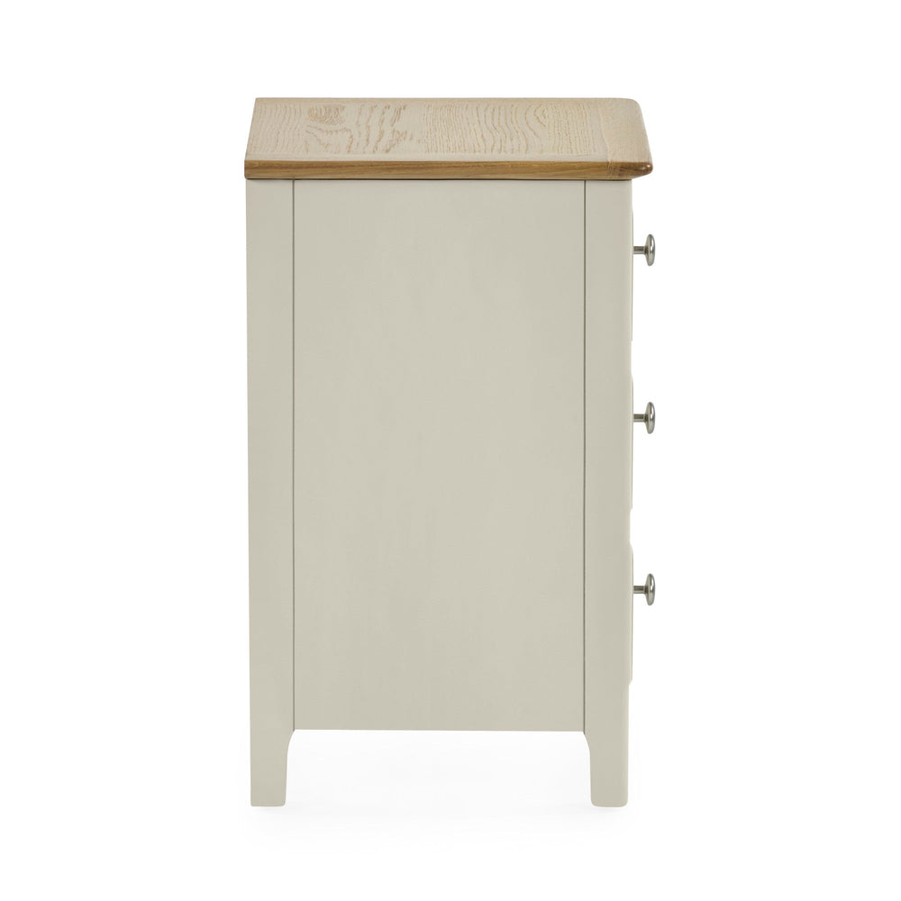 Side view of light grey bedside table showing flat panel design, natural wood top and silver drawer knobs